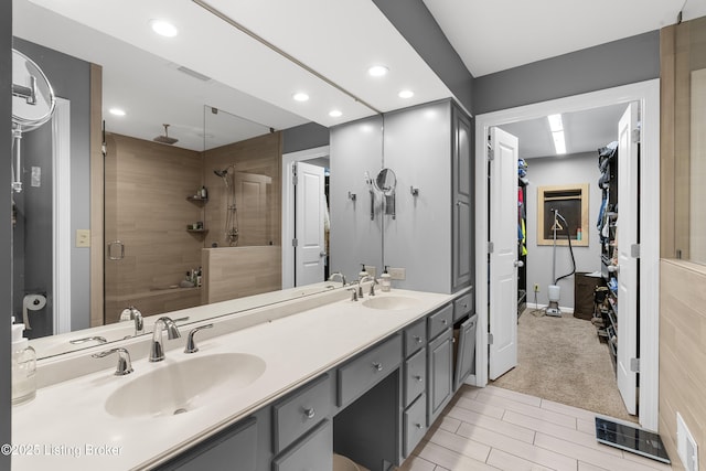 bathroom with a shower stall, recessed lighting, double vanity, and a sink