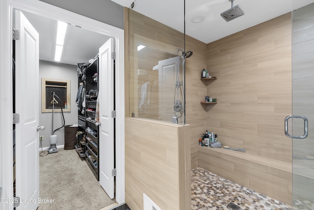 bathroom with a spacious closet and a tile shower