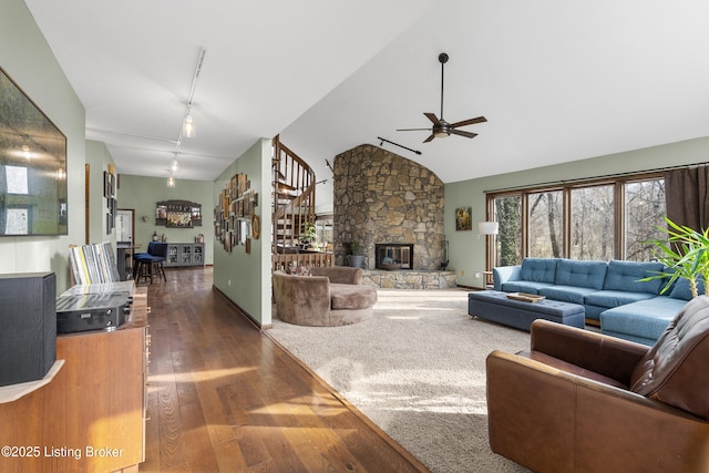 living room featuring track lighting, wood finished floors, a fireplace, ceiling fan, and stairs