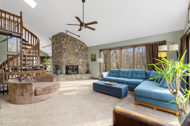 carpeted living area with stairs, high vaulted ceiling, a fireplace, and a ceiling fan