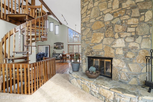 living area featuring high vaulted ceiling, stairway, a stone fireplace, and wood finished floors