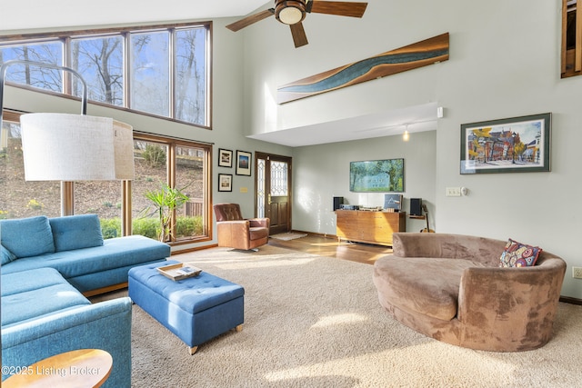 living room with baseboards, a towering ceiling, and ceiling fan