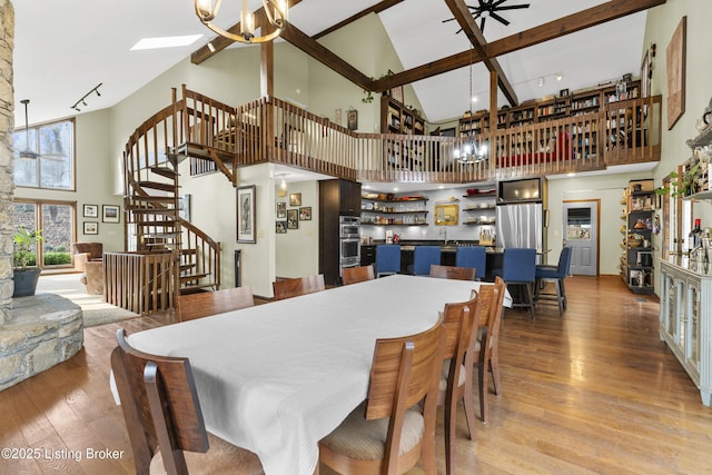 dining room with light wood finished floors, a chandelier, wet bar, a towering ceiling, and stairs