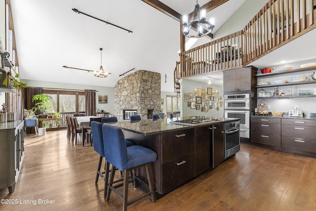 kitchen featuring a notable chandelier, open shelves, dark wood-style floors, appliances with stainless steel finishes, and a breakfast bar area