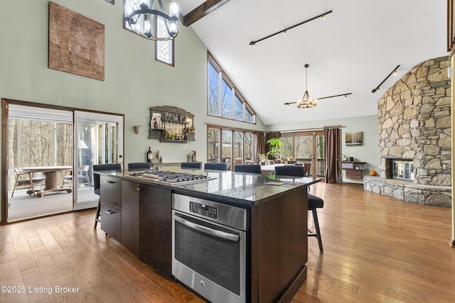 kitchen featuring an inviting chandelier, dark wood-style flooring, appliances with stainless steel finishes, a kitchen breakfast bar, and a center island