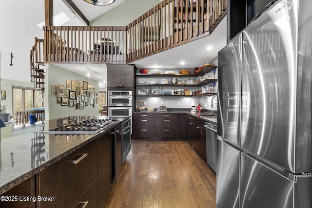 kitchen with dark brown cabinets, dark wood finished floors, a towering ceiling, stainless steel appliances, and open shelves