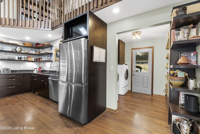 kitchen featuring open shelves, a sink, separate washer and dryer, appliances with stainless steel finishes, and dark wood-style flooring