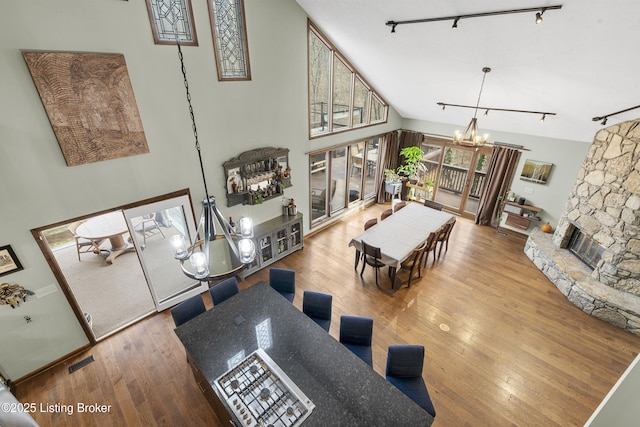 living room with visible vents, high vaulted ceiling, track lighting, wood-type flooring, and an inviting chandelier