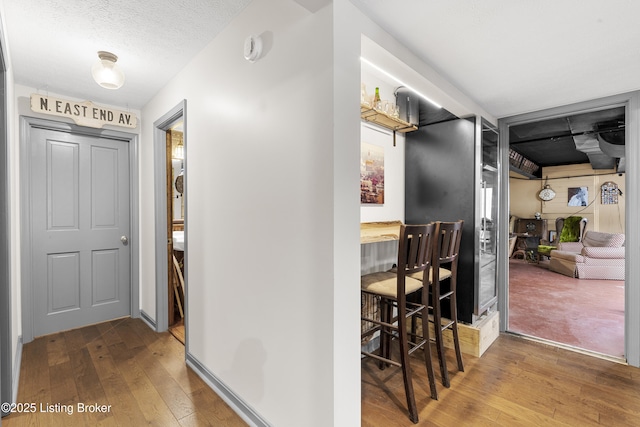 hallway with hardwood / wood-style floors and a textured ceiling