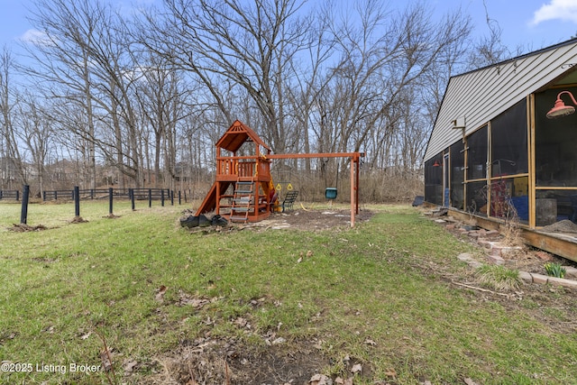 view of yard featuring a playground, fence, and a sunroom