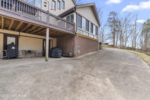 view of property exterior with a deck and concrete driveway