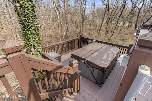 deck featuring a view of trees and a hot tub