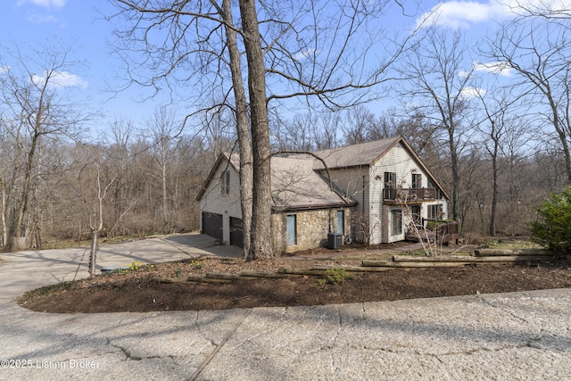 view of front facade featuring a garage, central air condition unit, a balcony, and driveway