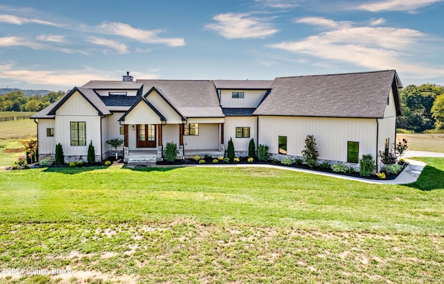 modern inspired farmhouse with a front yard, a chimney, and a shingled roof