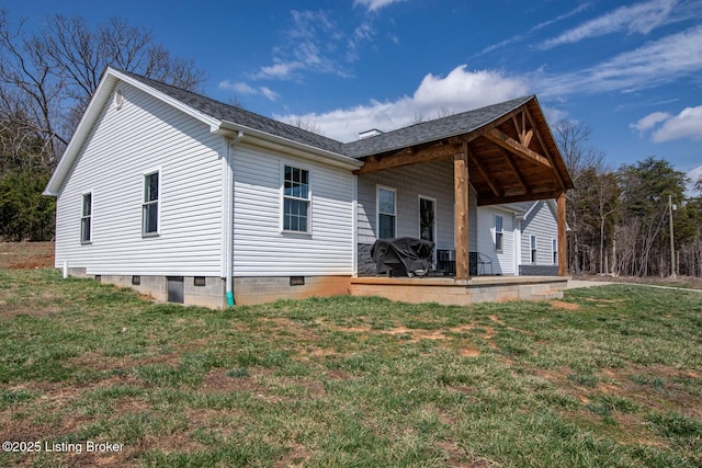 back of house with a patio, a lawn, and a shingled roof