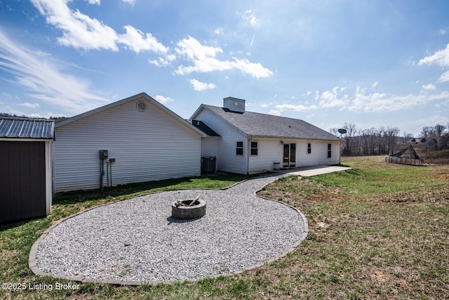 back of property with a patio, an outbuilding, cooling unit, a yard, and a fire pit