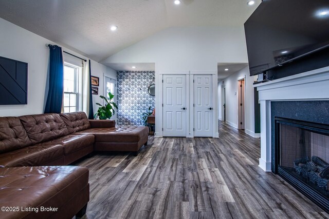 living room featuring baseboards, a fireplace, wood finished floors, a textured ceiling, and high vaulted ceiling