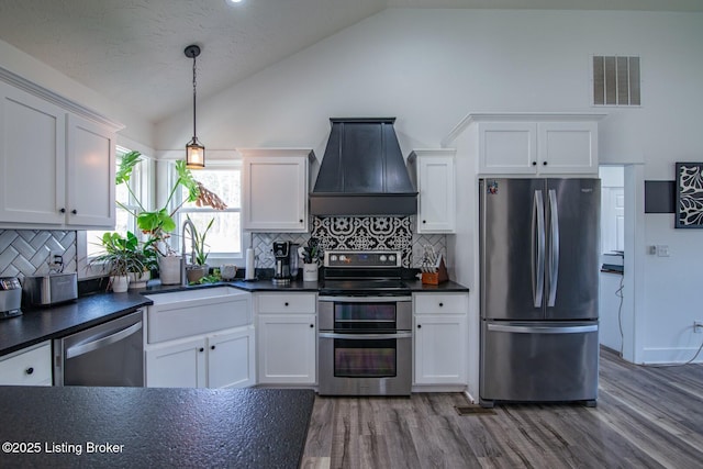 kitchen with visible vents, custom exhaust hood, white cabinets, appliances with stainless steel finishes, and dark countertops