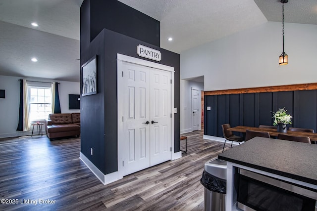 interior space with lofted ceiling, a textured ceiling, wood finished floors, recessed lighting, and baseboards