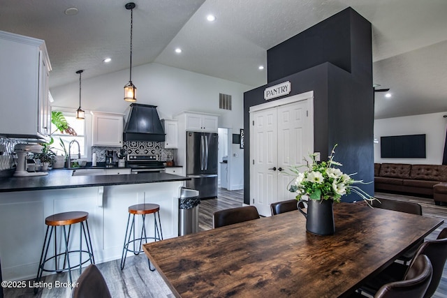 dining space featuring visible vents, recessed lighting, high vaulted ceiling, and wood finished floors