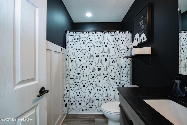 bathroom with vanity, curtained shower, toilet, and a textured ceiling