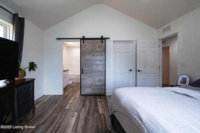 bedroom with visible vents, dark wood-type flooring, baseboards, a barn door, and vaulted ceiling