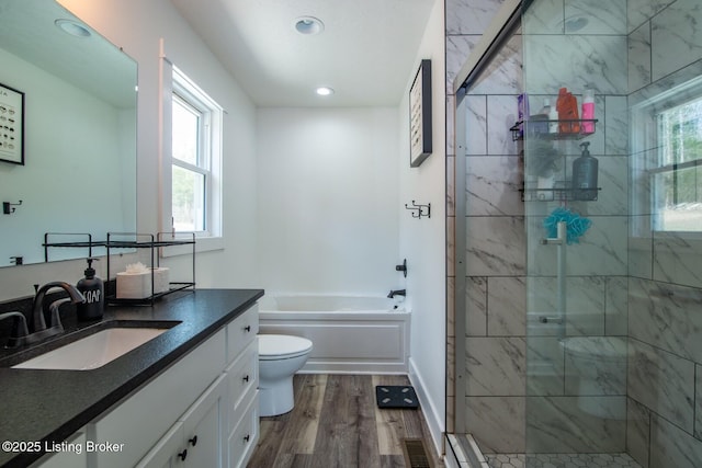 full bath with toilet, a stall shower, wood finished floors, a bath, and vanity