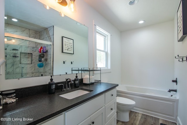 bathroom with vanity, wood finished floors, a shower stall, a garden tub, and toilet