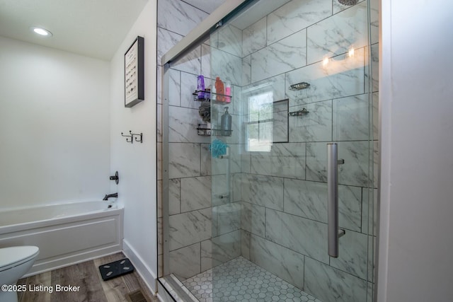 full bath with wood finished floors, baseboards, a stall shower, a garden tub, and toilet