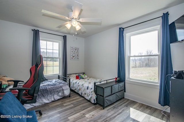 bedroom featuring baseboards, wood finished floors, and a ceiling fan