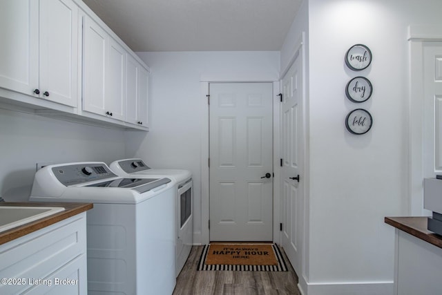 laundry room featuring cabinet space, washing machine and dryer, and wood finished floors