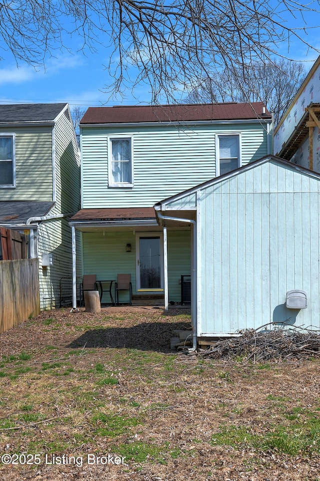 rear view of house with an outbuilding, a storage unit, and fence