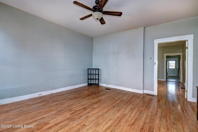 unfurnished room with wood finished floors, a ceiling fan, baseboards, and visible vents