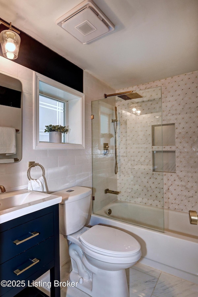 full bath with visible vents, toilet, vanity, combined bath / shower with glass door, and tile walls