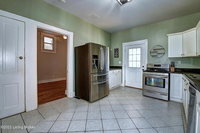 kitchen with light tile patterned floors, visible vents, dark countertops, and appliances with stainless steel finishes