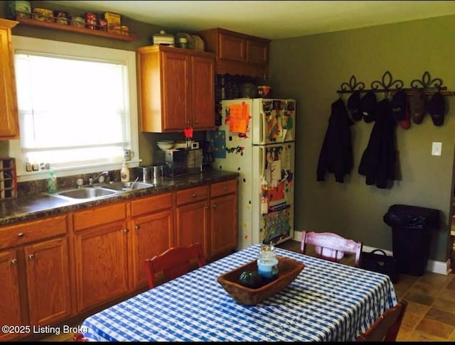 kitchen featuring dark countertops, freestanding refrigerator, and a sink