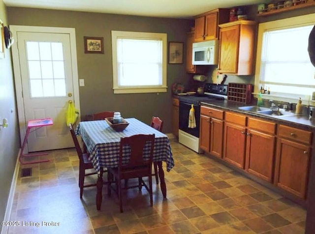 kitchen featuring electric range, a sink, dark countertops, brown cabinetry, and white microwave