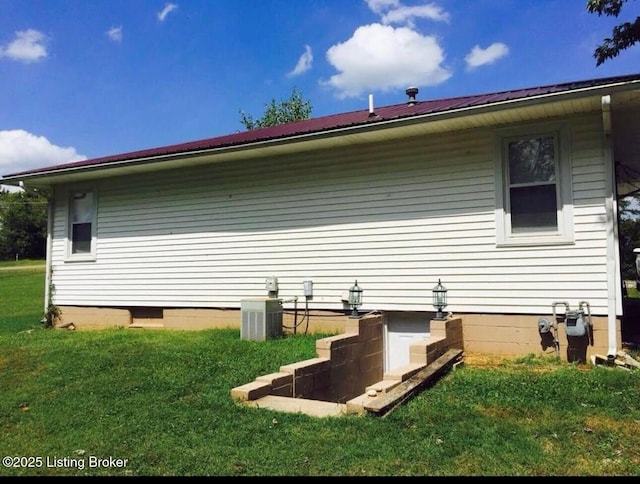 view of side of property with a yard, central AC unit, and metal roof