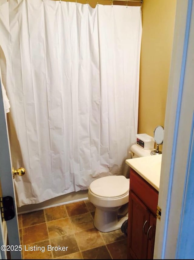 full bathroom with toilet, vanity, and stone finish floor