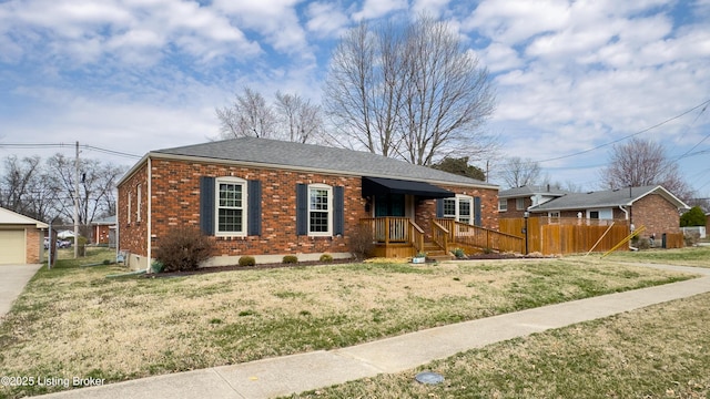 view of front facade with brick siding, a shingled roof, fence, a front yard, and a garage