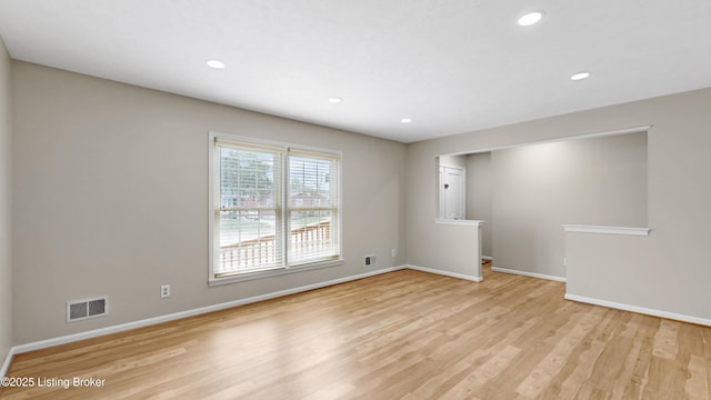 spare room with light wood finished floors, visible vents, and baseboards