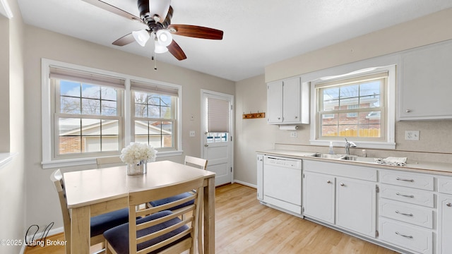 kitchen featuring ceiling fan, a sink, white cabinets, dishwasher, and light wood-type flooring