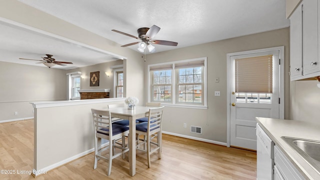 dining room featuring a ceiling fan, visible vents, light wood finished floors, and baseboards