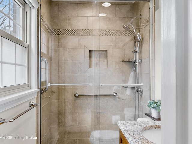 bathroom featuring vanity, a shower stall, and toilet