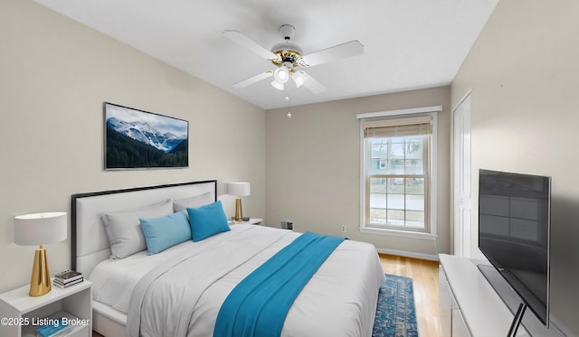 bedroom featuring light wood-type flooring, baseboards, and a ceiling fan