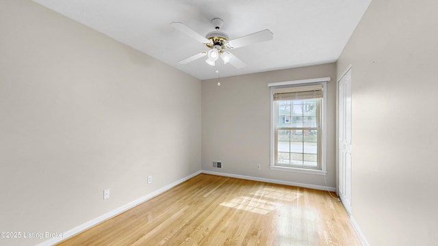 spare room featuring light wood-type flooring, baseboards, visible vents, and a ceiling fan