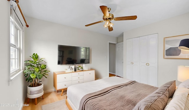 bedroom with light wood-type flooring, baseboards, a closet, and a ceiling fan