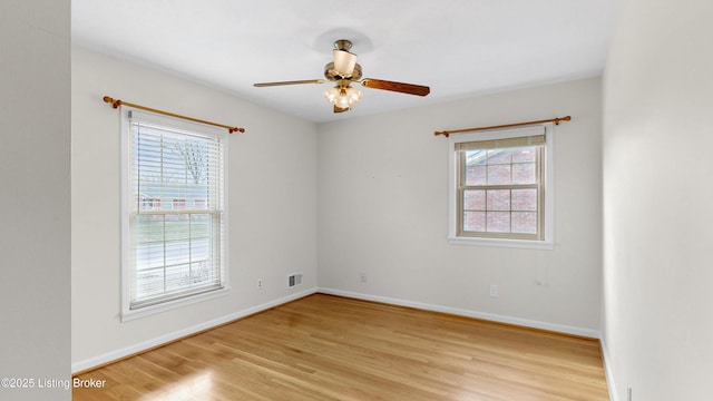 empty room with visible vents, a ceiling fan, light wood-type flooring, and baseboards