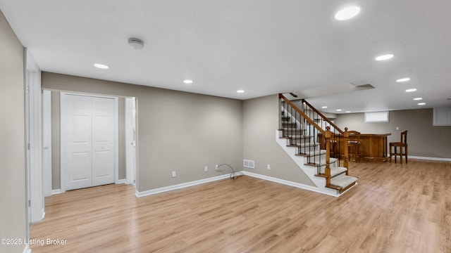 basement with light wood finished floors, recessed lighting, indoor bar, and baseboards