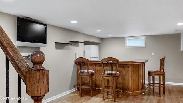 bar featuring freestanding refrigerator, recessed lighting, light wood finished floors, baseboards, and a dry bar